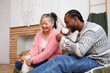 Smiling positive interracial couple spending time with coffee and dog at home