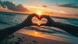 Couple hands making heart symbol on sunset beach background, love and compassion concept.