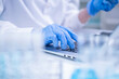 © Supapich - Closeup woman female scientist's hand blue protective glove using laptop for recording scientific medical experiment research from laboratory