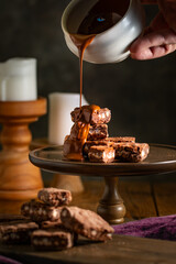 Wall Mural - Pouring melted chocolate over brownies.
Bakery, confectionery concept.