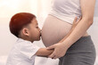 © lllonajalll - Little boy Kissing the belly of the pregnant mother. Pregnant mother and son are happy. little child boy looking at her mother's pregnant tummy