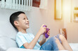little Asian boy playing a video game. shot of a child holding a game controller. A kid is smiling and playing happily.