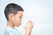 © lllonajalll - little Asian boy drinks water from a glass. shot of a child drinking a glass of cold water.