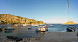 Panorama shot of motor boats parked at a dock named Agios Nikolaos harbour against blue sea and mountain in one of the ionian island of Zakynthos, Greece