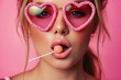 A playful woman embraces her femininity with bold cosmetics, as she dons heart shaped sunglasses and a lollipop in hand