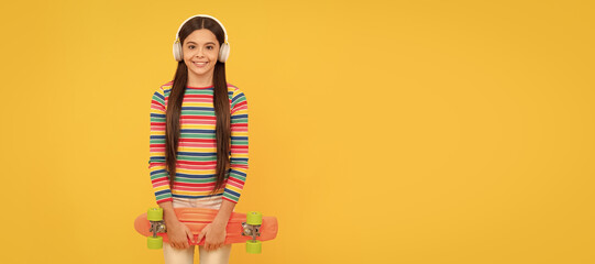 Wall Mural - happy teen girl skateboarder listen music in headphones with penny board skateboard, childhood. Casual teen child horizontal poster. Banner header, copy space.