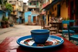 Fototapeta Fototapeta uliczki - Morning coffee cup on table in charming narrow streets of old city with blooming flowers