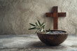 Ash Wednesday, faith, liturgy, religious ceremony background. Wooden cross, ceremonial dish with ash and olive branch on gray background
