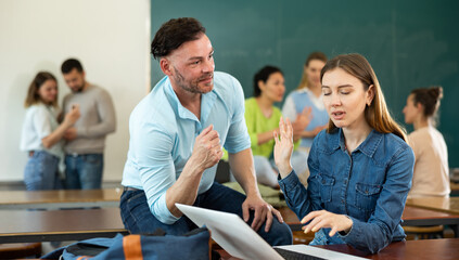 Sticker - Student girl studying on a laptop during a break after classes refuses the help of a fellow student who approached her