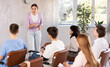 © JackF - Young woman lecturer conducting lesson for group of interested adult students sitting on chairs in auditorium