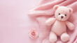 A small knitted amigurumi bear toy on a pink blanket, on a pink background. Flat lay, top view, copy space. space for text