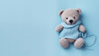 A small knitted amigurumi bear toy on a blue blanket, on a blue background. Flat lay, top view, copy space. space for text