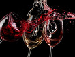 Red, white and rose wine glasses splash, close up on black background