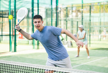 Wall Mural - Focused teenager playing friendly paddleball match on outdoor summer court. Concept of concentration in competition..