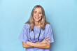 © Asier - Young caucasian nurse in blue studio laughing and having fun.