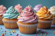 © Elle Arden  - Delicious cupcakes with different colors of buttercream frosting and sprinkles on a blue background.