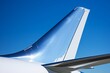 Close-up of a modern airplane's winglet or sharklet against a backdrop of a bustling airport and clear blue sky