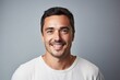 © Iigo - Portrait of a handsome young man smiling at camera against grey background
