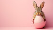 Cute Easter bunny hatching from pink Easter egg isolated on pastel pink background with copy space.