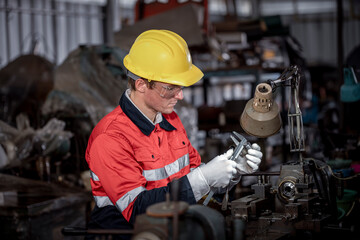 Industry engineer wearing safety uniform used vernier caliper to measure the object control operating machine working in industry factory is metal manufacturing machine industry concept.