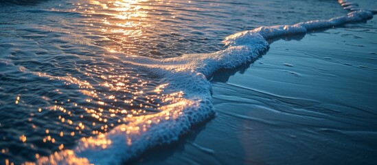 Wall Mural - A wind wave is breaking on the water at the natural landscape of the beach during sunset, with the horizon painted in electric blue hues.