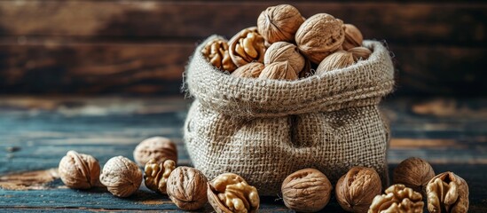 Wall Mural - Walnuts in a rustic sack on a wooden background.