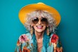 © Iigo - Portrait of smiling senior woman in hat and sunglasses on blue background