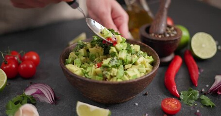 Wall Mural - Salsa recipe - Woman mixing Chopped ingredients in wooden bowl - avocado, onion, cilantro and pepper