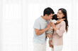 © geargodz - father and mother holding and hugging with toddler baby on white window background. happy family