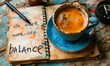 Concept of work life balance represented with a notepad filled with related words next to a blue coffee cup and pen on a wooden table