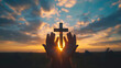 Silhouette of hands and a cross on sunset sky background