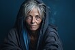  An older homeless woman, 55 years old, grappling with mental health challenges, emphasizing the vulnerability of homeless individuals on a solid muted navy background.