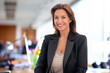 © sepy - Brunette haired mid aged businesswoman standing at the office and cheerful smiling
