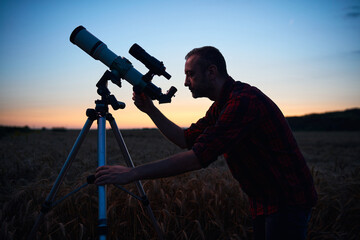 Wall Mural - astronomer looking at night sky with a telescope.
