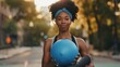 Afro-american fit woman holding pilates ball in the gym outdoor, smiling