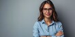 Cheerful youthful grinning self-assured corporate lady donning navy top and spectacles elated attractive woman boss gazing at the lens with folded arms standing alone against a grey backdrop headshot.