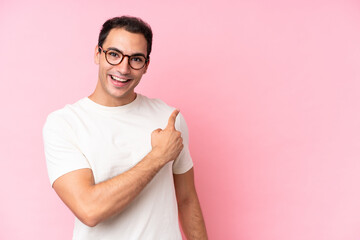 Wall Mural - Young caucasian man isolated on pink background surprised and pointing side