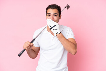 Young golfer player man isolated on pink background happy and smiling covering mouth with hand