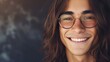 © Z A C - A young man with long hair and glasses smiling at the camera with a warm and inviting expression.