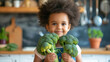 Close up face shot of cute African girl in front of healthy vegetable broccoli. Upset toddler refuses to eat healthy meal because she is a picky eater. Disgusted african girl holding broccoli.