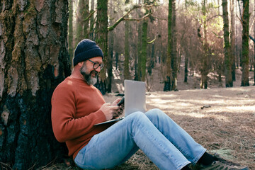 Wall Mural - One man using technology connection in nature park forest woods. Remote worker small travel business lifestyle people. Working in the nature alternative office. Small business. Travelers job life