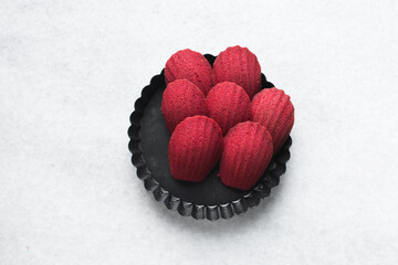 Sticker - Top view of Red velvet madeleines in a black tart tin, red madeleines cake or cookies on a white background