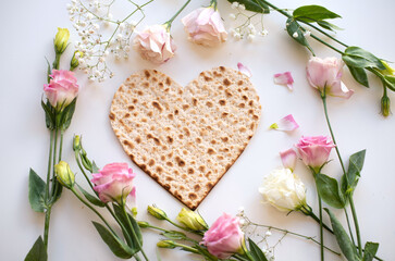 Wall Mural - Passover. Traditional Matzo shape of heart decorate by pink flowers on white background. top view. Holiday of Jewish people, Spring Holiday. Fasting time