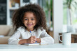 © Darya Lavinskaya - Happy african American little girl with curly hair sitting at the table, writing and doing homework