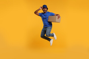 Wall Mural - Happy courier with parcel jumping on orange background