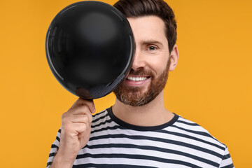 Canvas Print - Happy man with black balloon on yellow background