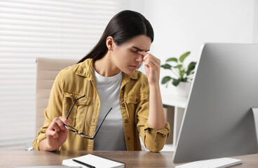 Canvas Print - Young woman suffering from headache at wooden table in office