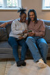 Happy couple using phone while sitting on sofa