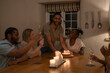 © Cultura Creative - Man brings birthday cake to friend at table
