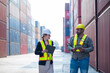 © Washburn - Warehouse engineer inspects merchandise with large customer at industrial container yard.